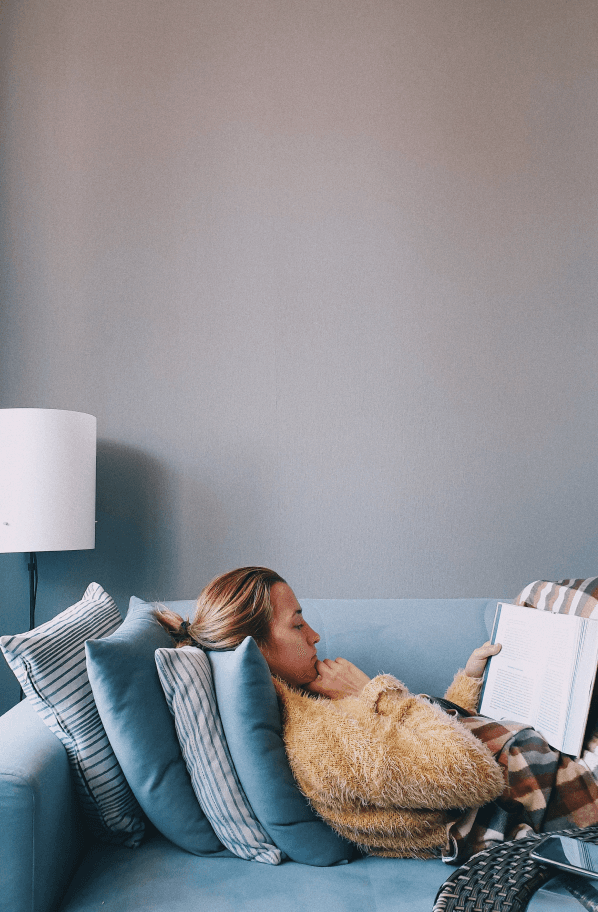 Image of a girl on the couch reading a book